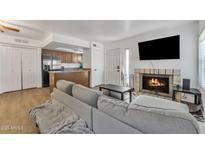 Comfortable living room featuring a gray sofa, a cozy fireplace, and an eat-in kitchen at 10015 N 14Th St # 10, Phoenix, AZ 85020