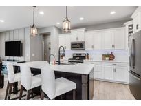 Bright kitchen features white cabinets, a large island with seating, and modern appliances at 1437 W Smoke Tree Ave, San Tan Valley, AZ 85140