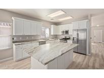 Bright kitchen features white cabinets, stainless steel appliances, and large island with stone countertop at 8134 E Obispo Ave, Mesa, AZ 85212