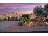 Charming single-story home showcasing well-manicured landscaping and a two-car garage at dusk at 13655 W Junipero Dr, Sun City West, AZ 85375