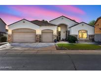 Beautiful single-story home featuring a three-car garage, stone accents, and arched entryway at 17591 W Ivy Ln, Surprise, AZ 85388