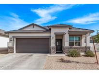 Charming single-story home featuring a stone-accented facade, gray trim, and a two-car garage at 4051 S 243Rd Dr, Buckeye, AZ 85326