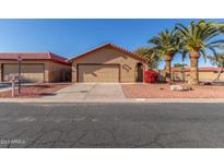Charming single-story home with a beige facade, a red tile roof, and desert landscaping featuring palm trees at 4910 E Yuma St, Phoenix, AZ 85044