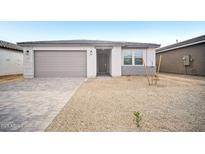 Charming single-story home featuring a gray driveway, two car garage and desert landscaping at 9529 W Luxton Ln, Tolleson, AZ 85353