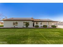 Beautiful ranch-style home with a well-manicured front lawn, covered porch, and solar panels at 13447 S 155Th St, Gilbert, AZ 85296