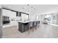 Modern kitchen boasts white cabinets, stainless steel appliances, and a large center island with seating at 1957 W Lonesome Trl, Phoenix, AZ 85085