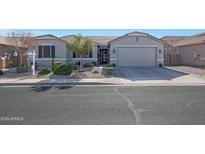 Charming single-story home with a well-manicured lawn, desert landscaping, and a two-car garage, all in a warm and inviting color palette at 22805 W Hopi St, Buckeye, AZ 85326