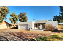 Charming single-story home with stucco exterior, attached garage, desert landscaping and a concrete driveway at 1344 E Grove Cir, Mesa, AZ 85204