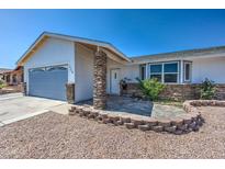 Charming single-story home with a stone facade, well-maintained landscaping, and attached garage under a clear blue sky at 3728 E Grove Ave, Mesa, AZ 85206