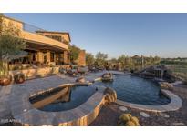 A luxurious pool with spa, waterfall feature, stone accents, and patio furniture overlooks the Arizona landscape at 9161 E Superstition Mountain Dr, Gold Canyon, AZ 85118
