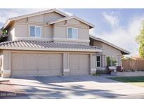 Tan two-story home with a three car garage, tile roof and manicured lawn at 1320 N Desoto St, Chandler, AZ 85224