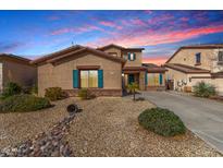 Charming single Gathering home featuring desert landscaping, blue shutters, and a well maintained lawn at 18060 W Rimrock St, Surprise, AZ 85388