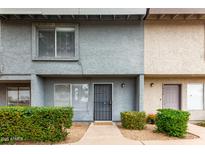 Charming townhouse featuring a secure black metal front door, concrete walkway and manicured bushes at 19601 N 7Th St # 1009, Phoenix, AZ 85024
