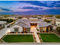 Stunning aerial view of a luxury home with beautiful landscaping, pool, and city views during twilight at 2656 E Oriole Dr, Gilbert, AZ 85297