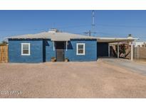 Charming blue home with a covered parking area and a small gravel front yard at 2910 W Madison St, Phoenix, AZ 85009