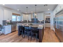 A modern kitchen featuring white cabinets, stainless steel appliances, and a large island with bar seating at 4306 E Flower St, Phoenix, AZ 85018
