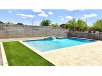 Sparkling pool with water feature, stone surround, and artificial turf, perfect for relaxation and outdoor enjoyment at 5345 W Leodra Ln, Laveen, AZ 85339