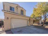 Two-story home featuring a garage, tan stucco exterior and a well-kept lawn at 10423 W Hughes Dr, Tolleson, AZ 85353