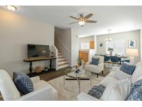 Inviting living room featuring hardwood floors, a ceiling fan, and stairs leading to the second floor at 16219 W Woodlands Ave, Goodyear, AZ 85338