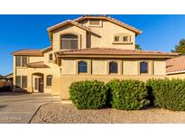 Two-story stucco home with a tile roof, arched windows, and lush, flowering bushes in the front yard at 16528 W Pierce St, Goodyear, AZ 85338