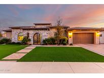 Elegant stone home featuring an arched entry gate, manicured lawn, and attached two car garage at 2799 E Waterman St, Gilbert, AZ 85297