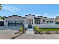 Beautiful home featuring a glass garage door, manicured lawn, and walkway leading to the front door at 3511 E Orange Dr, Phoenix, AZ 85018