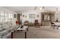 Comfortable living room with ceiling fan, neutral carpeting, and bright natural light at 8233 E Calypso Ave, Mesa, AZ 85208