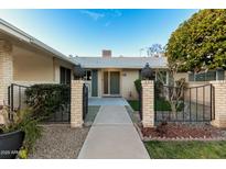 Welcoming front entrance features a walkway and a charming brick wall, complete with lush landscaping and a vibrant tree at 10808 W Kelso Dr, Sun City, AZ 85351