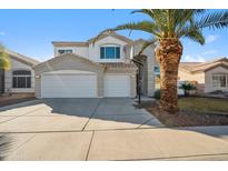 Two-story stucco home with a three car garage and a mature palm tree in the front yard at 11537 W Laurelwood Ln, Avondale, AZ 85392