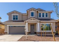 Two-story home featuring tan stucco, a gray garage door, and a well-manicured front yard at 20941 E Via Del Sol St, Queen Creek, AZ 85142