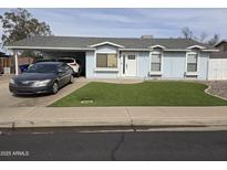Charming single-story home with blue siding, well-manicured lawn, and covered parking area at 2726 E Harmony Ave, Mesa, AZ 85204