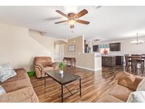 Open-concept living room with staircase, wood-look flooring, and comfortable sofa and armchair at 317 W Settlers Trl, Casa Grande, AZ 85122
