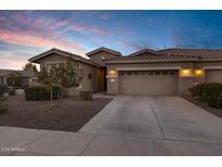 Charming single-Gathering home featuring a desert landscape, tile roof, and a two-car garage against a blue sunset sky at 42072 W Dorsey Dr, Maricopa, AZ 85138