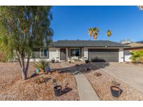 Charming single-story home featuring a two-car garage, desert landscaping, and mature palm trees on a sunny day at 520 E Jahns Pl, Casa Grande, AZ 85122