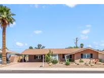 Charming single-story home featuring a covered carport, desert landscaping, and a mature palm tree at 7526 E Edgemont Ave, Scottsdale, AZ 85257