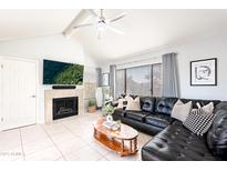 Bright living room with fireplace, ceiling fan and large black leather couch at 10115 E Mountain View Rd # 2112, Scottsdale, AZ 85258