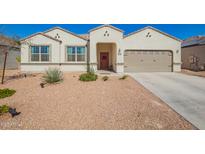 Charming single-story home with desert landscaping, two-car garage, and a welcoming red front door at 30876 W Verde Ln, Buckeye, AZ 85396