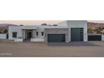 Modern home featuring a clean white design with gray garage doors, brick accents, and mountain views at 37931 N 31St Ave, Phoenix, AZ 85086