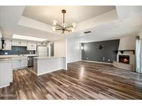 Open concept living room featuring a fireplace, modern light fixture, and wood-look flooring at 8344 N 21St Dr # I105, Phoenix, AZ 85021