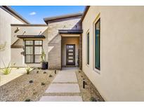 Modern home's exterior showcases a stone-accented entrance and desert landscaping, creating a welcoming and stylish curb appeal at 14543 N Adero Canyon Dr, Fountain Hills, AZ 85268