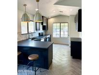 Modern kitchen featuring dark cabinets, sleek countertops, stainless steel appliances, and stylish pendant lighting at 21824 N 32Nd Ave, Phoenix, AZ 85027