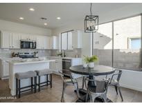 Bright kitchen boasts white cabinets, tiled backsplash, stainless appliances, and an island with bar seating at 39237 N Acadia Way, Anthem, AZ 85086