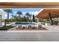 Stunning backyard pool area with lounge chairs, umbrellas, and outdoor entertainment space with a fireplace at 11222 N 73Rd St, Scottsdale, AZ 85260