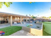 Spacious backyard featuring a covered patio, outdoor seating, putting green, and fenced pool for entertainment at 15035 N 54Th St, Scottsdale, AZ 85254