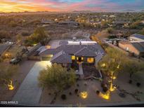 Stunning aerial view of desert home with a tile roof and circular drive surrounded by desert landscape and mountains at 27606 N 61St Pl, Scottsdale, AZ 85266