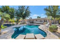 Inviting pool with rock waterfall feature and seating, surrounded by lush greenery and patio space at 6420 E Gary Rd, Scottsdale, AZ 85254