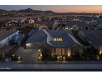 Inviting single-Gathering home with manicured lawn, paver driveway, and mountain views at dusk at 1899 E Everglade Ln, Gilbert, AZ 85298