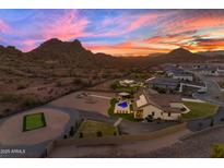 Expansive property featuring a pool, sport court, putting green, and mountain views at sunset at 297 W Chase St, San Tan Valley, AZ 85143