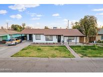 Charming single-story home boasts a well-manicured front yard and covered porch swing at 3331 W Sells Dr, Phoenix, AZ 85017