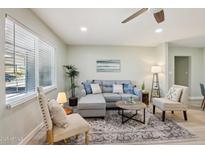 Bright living room featuring a gray sofa, accent chairs, stylish rug, and ceiling fan at 4235 N 16Th Dr, Phoenix, AZ 85015